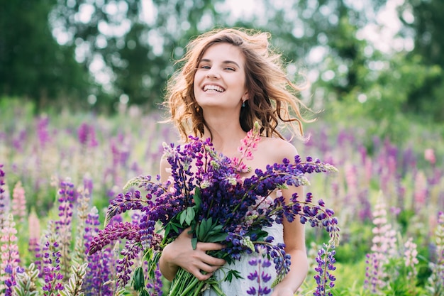 Girl with a bouquet of lupine on the field