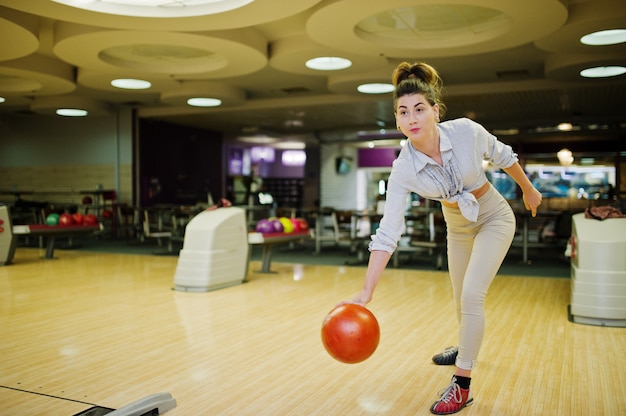 Girl with bowling ball on alley played at bowling club. 