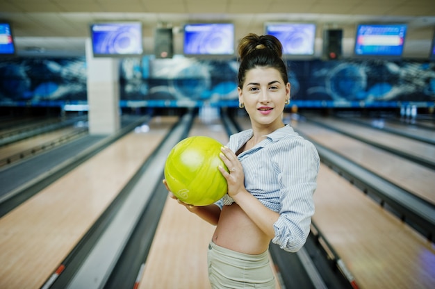 Girl with bowling ball on alley played at bowling club. 