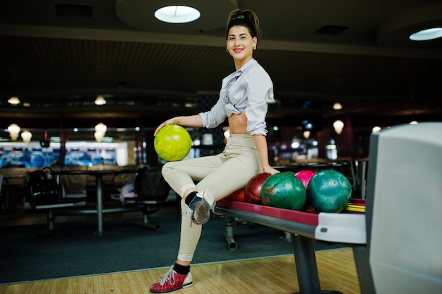 Girl with bowling ball on alley played at bowling club. 