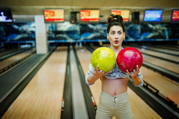 Girl with bowling ball on alley played at bowling club. 