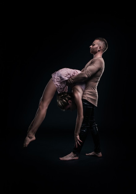 Girl with boyfriend perform beautiful gymnastic elements. 
beautiful acrobatic couple. black background