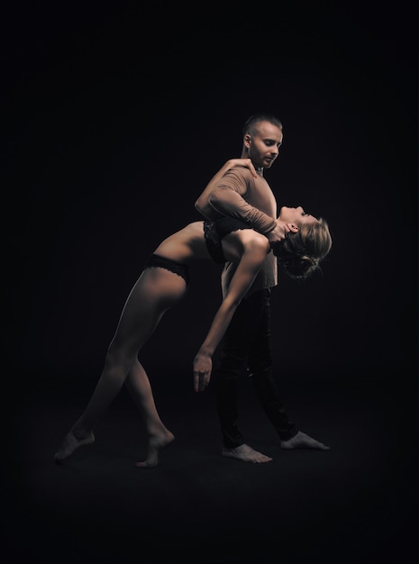 Girl with boyfriend perform beautiful gymnastic elements. 
beautiful acrobatic couple. black background