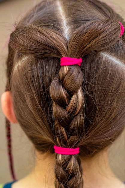 Photo a girl with a braided hair is wearing a pink hair tie.