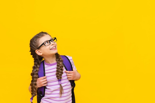 A girl with a briefcase looks up at your advertisement very happily A child on a yellow isolated background with a briefcase