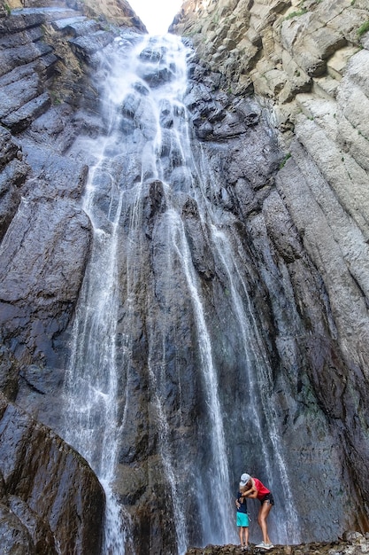 A girl with a child on the background of the AbaiSu waterfall KabardinoBalkaria June 2021