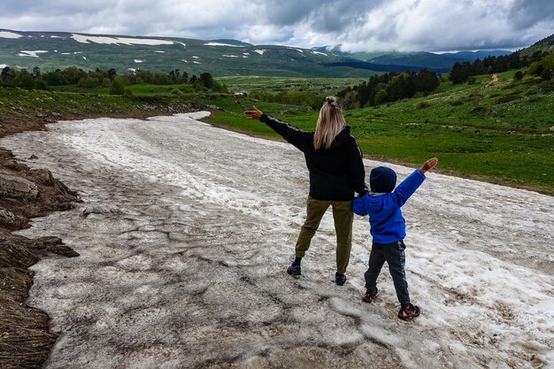 A girl with a child on a glacier on the snowy plateau of Lagonaki in Adygea Russia 2021