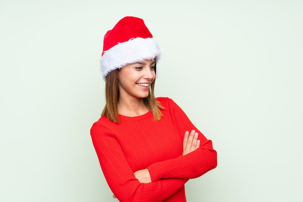 Girl with christmas hat over isolated green laughing