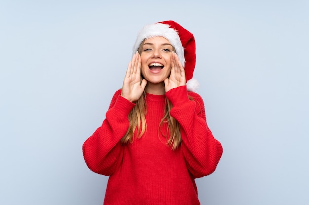 Girl with christmas hat and shouting over blue background