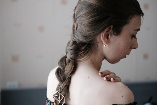 Girl with a classic braid with bare shoulders rear view