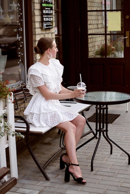 a girl with a cocktail. a girl is sitting at a table in a cafe