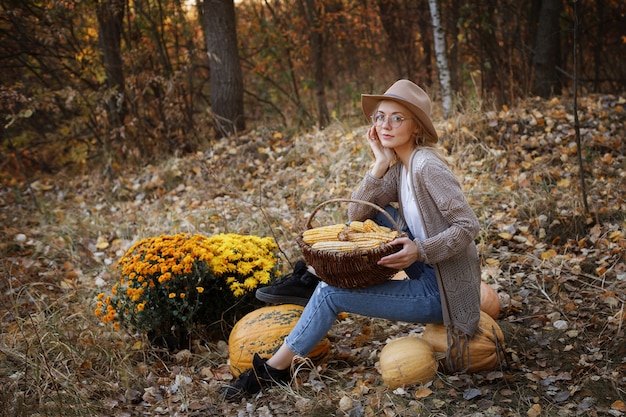 Girl with corn and pumpkin harvest in autumn