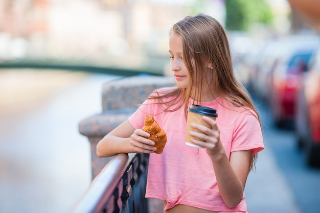 Girl with a croissant and coffee outdoors on the promenade