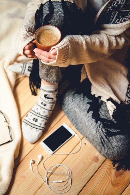 Girl with a cup of coffee sitting on a wooden floor