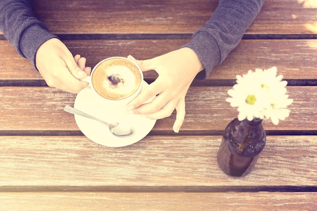 Girl with a cup of coffee at the wooden table