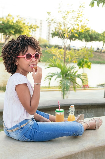 Girl with curly hair eating vegetables while sitting in a park