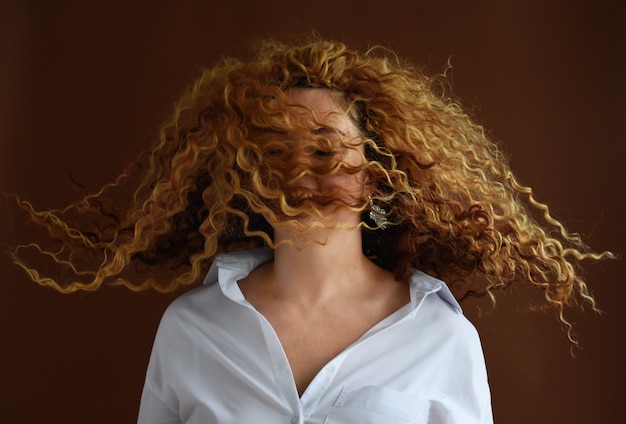 girl with developing hair is photographed in the studio on a brown background