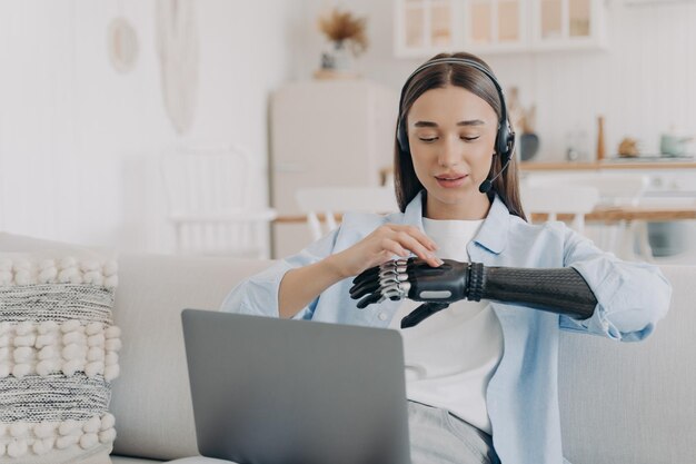 Girl with disability in headset customizes bionic prosthetic at laptop Lifestyle of disabled people