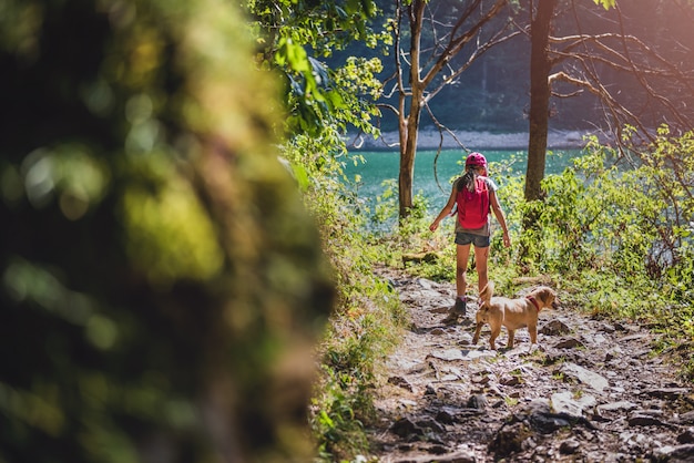 Girl with a dog hiking by the lake