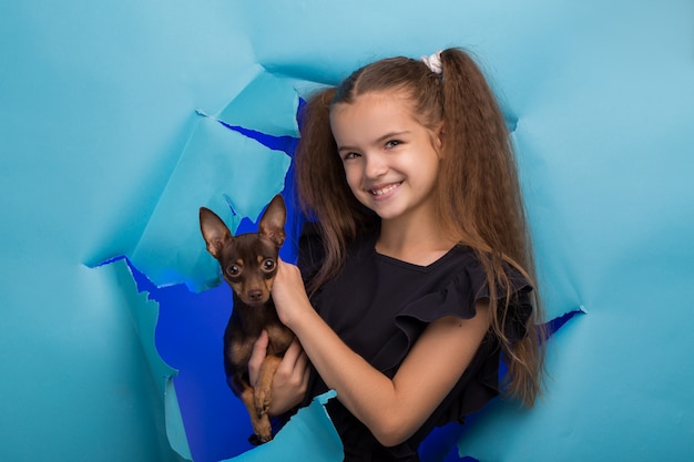 Girl with a dog peeps into a hole in blue paper