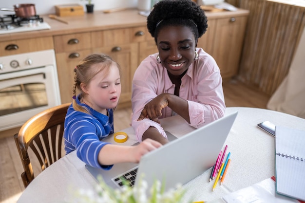 A girl with down syndrome having a lesson with her teacher and looking involved