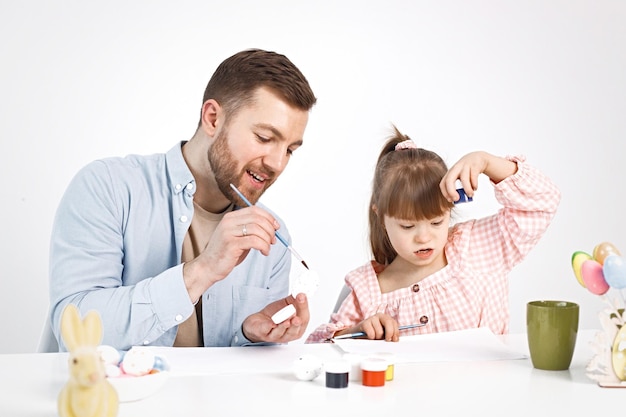 Girl with Down syndrome and her father painting Easter colored eggs