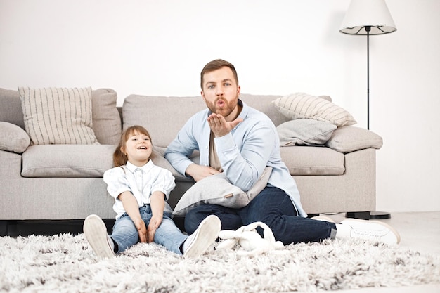 Girl with Down syndrome and her father sitting on a floor and talkiing together