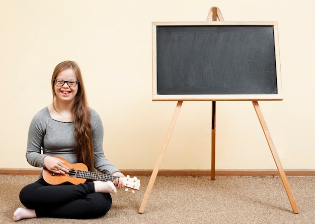 Girl with down syndrome posing with guitar and blackboard