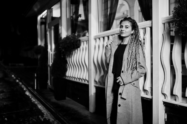 Girl with dreadlocks walking at night street of city.