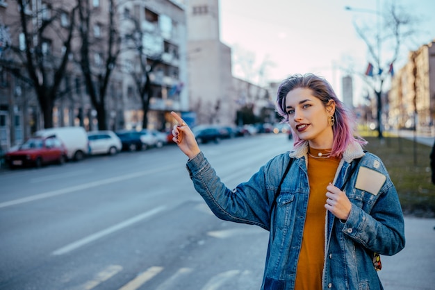 Girl with dyed hair hailing a cab.