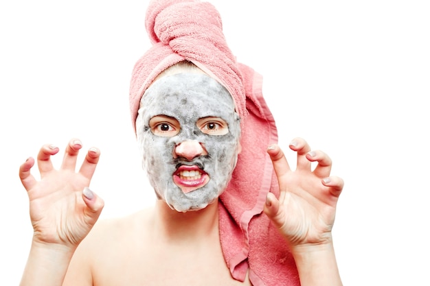 Girl with face mask, oxygen mask for face, girl looks after the skin of the face close-up portrait of a girl with a pink towel on her head on a white background isolated, aggressive girl, pampering