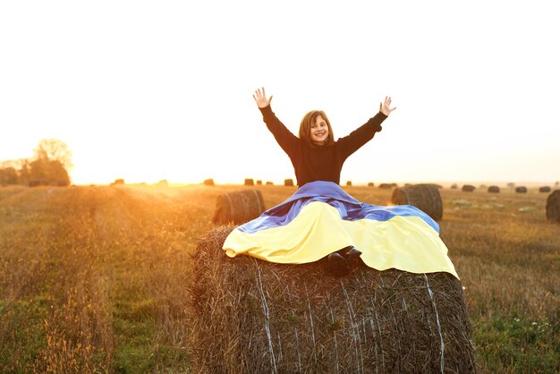 Girl with flag of ukraine sits the field at sunset portrait of little girl holding a yellow and blue