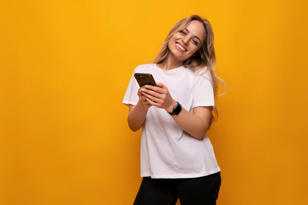 A girl with a gadget in her hands makes an order on the internet on a yellow background