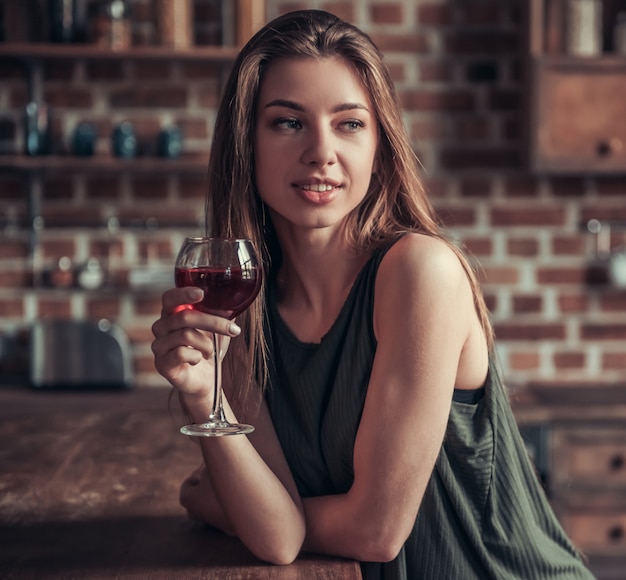 Girl with a glass of red wine looks away.