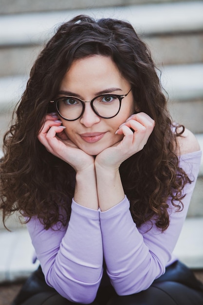 A girl with glasses on her face sits on steps