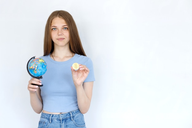 Girl with a globe and bitcoin on a gray background. work online