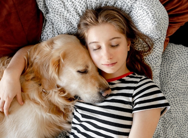 Girl with golden retriever dog in bed