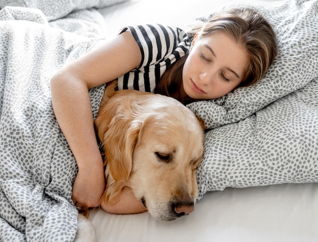 Girl with golden retriever dog in bed