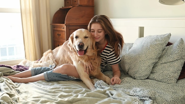 Girl with golden retriever dog in bed