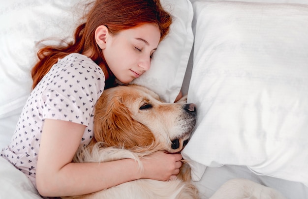 Girl with golden retriever dog in the bed