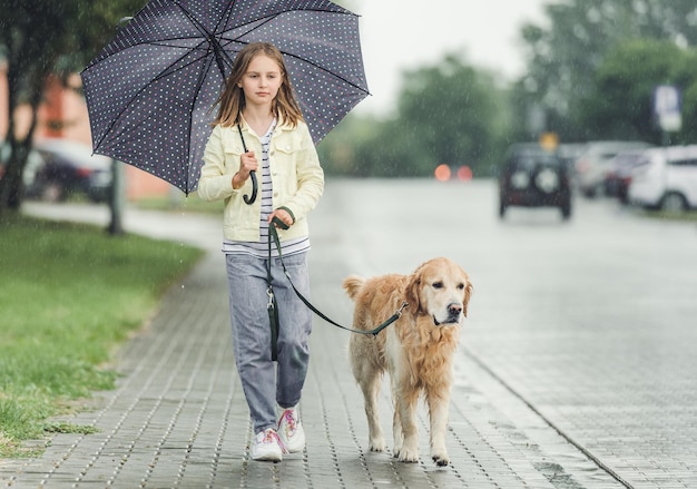 Girl with golden retriever dog in rainy day