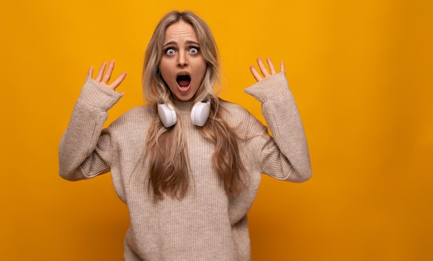 Girl with a grimace in headphones on a yellow background