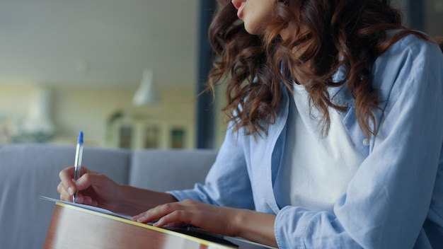 Girl with guitar writing music at home Guitarist making notes in notebook