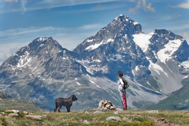 A girl with her big black dog in the mountain takes in the view