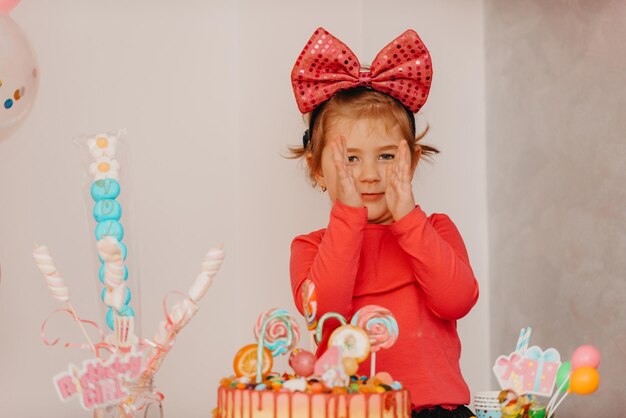 Girl with her birthday cake, happy birthday card, a cute little girl celebrates her birthday surrounded by gifts. High-quality photo