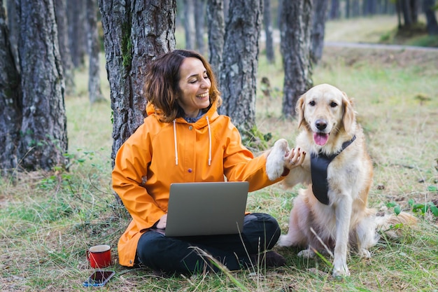 Girl with her computer and her dog outdoors