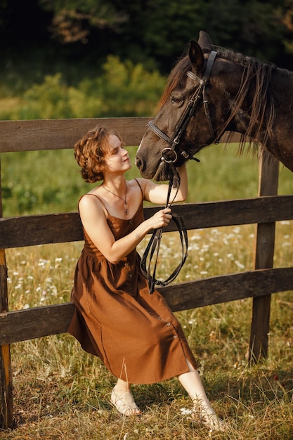 A girl with a horse a brown dress a man in nature with an animal