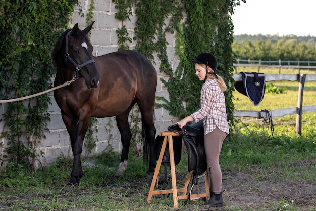 Girl with horse putting on saddle to go horseback riding