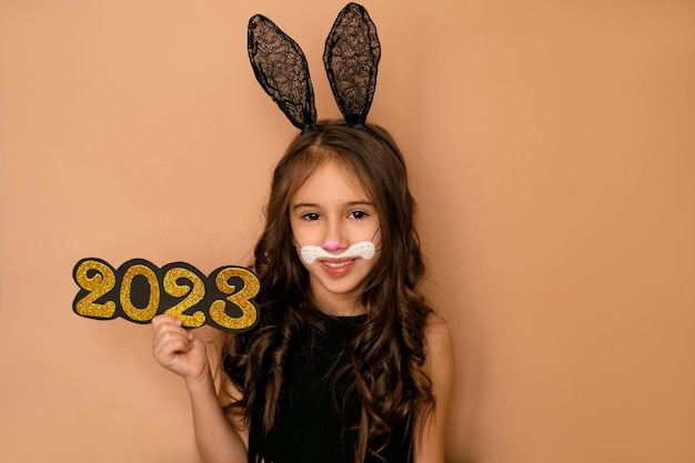 Girl with lacy rabbit ears holds number 2023 of new year