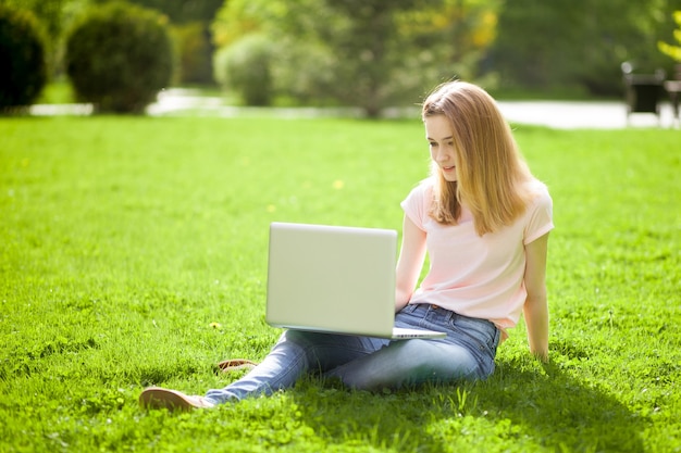 Girl with a laptop sitting on the lawn